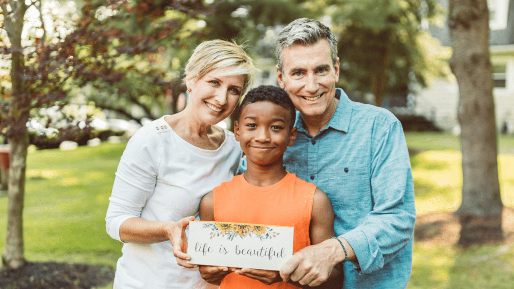 A couple and a boy holding a sign.