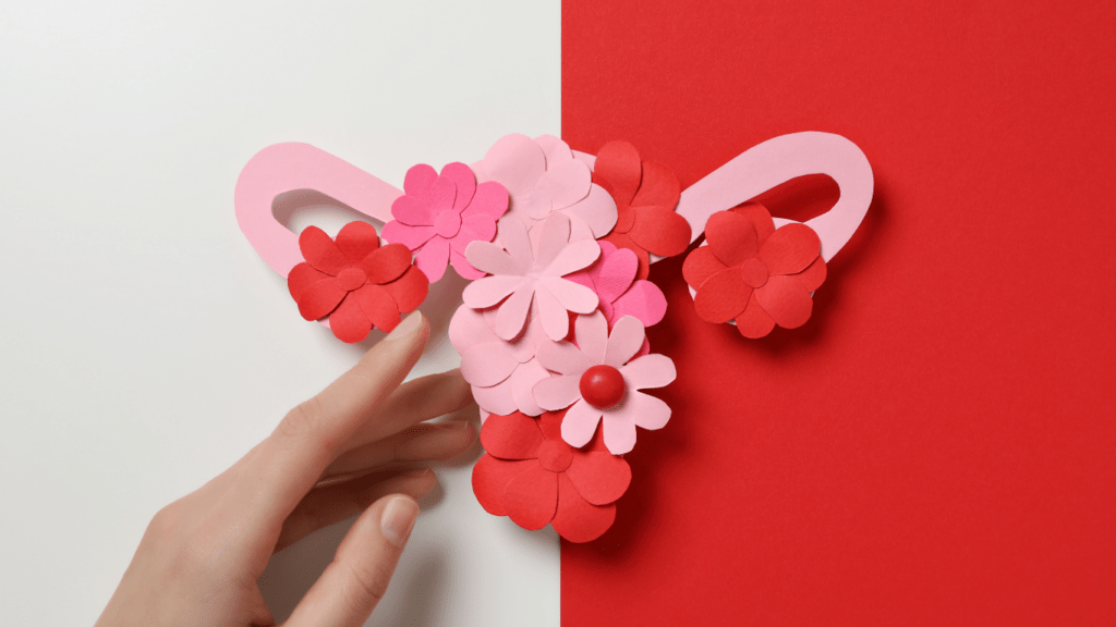A hand is holding a paper cutout of a uterus