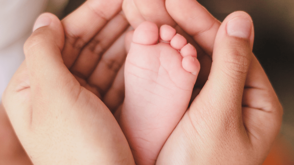 A person holding a baby's foot in their hands