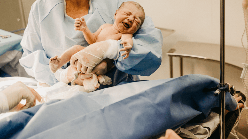 A person is holding a baby in an operating room