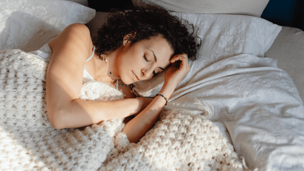 A person sleeping in bed with a blanket
