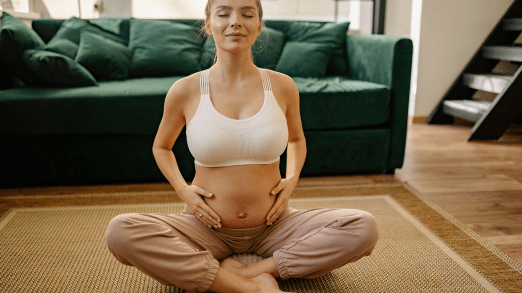 A pregnant person is sitting on the floor in front of a couch