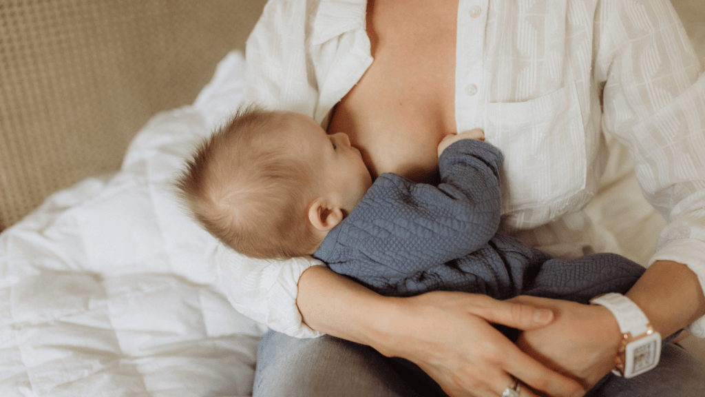 A person breastfeeds a baby while sitting in a chair.