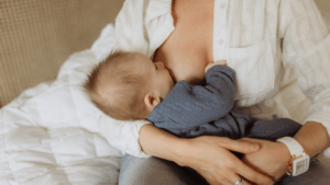 A person breastfeeds a baby while sitting in a chair.