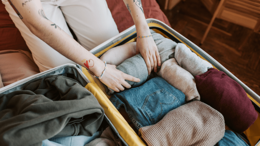 a person sitting on a bed with a suitcase full of clothes