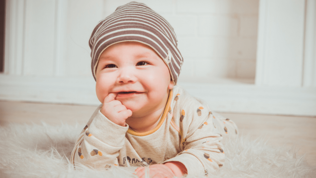 a smiling baby laying on the floor