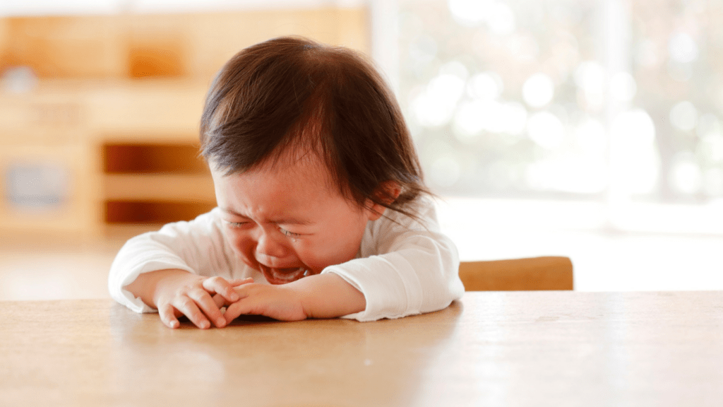 a crying baby sitting in the table