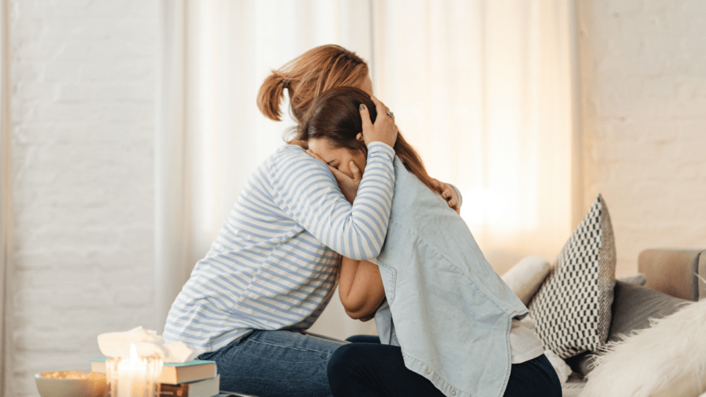 two people hugging on a couch in a living room