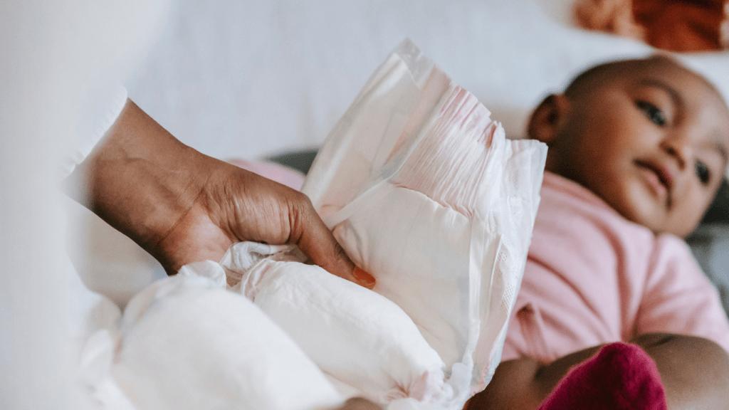 A person putting a diaper on a baby
