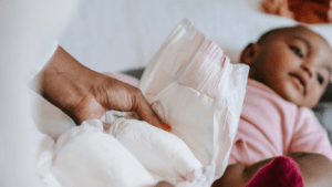 A person putting a diaper on a baby