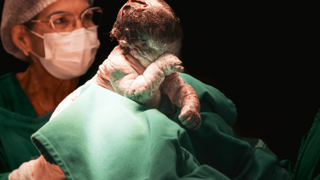 A person is holding a baby in an operating room