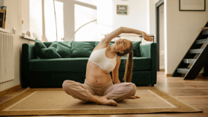 A pregnant person is sitting on the floor in front of a couch.png