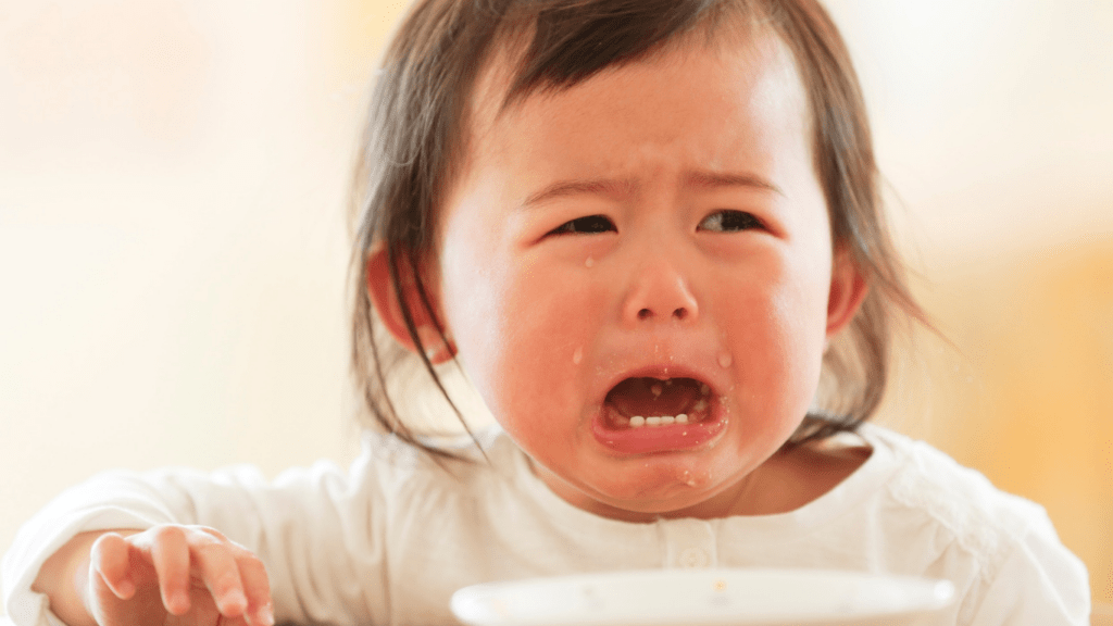a crying baby sitting in the table