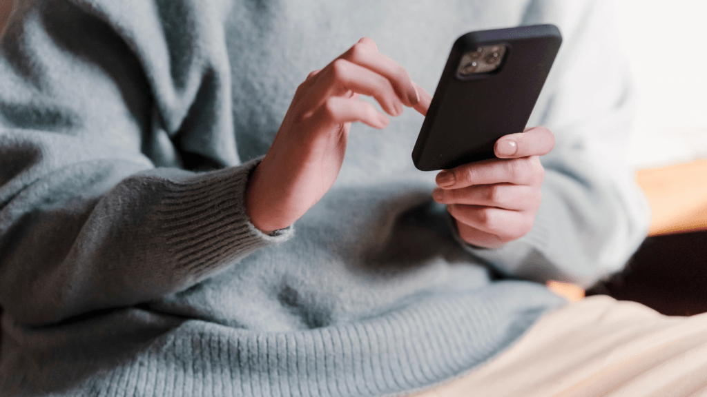 a person in a sweater holding a cell phone