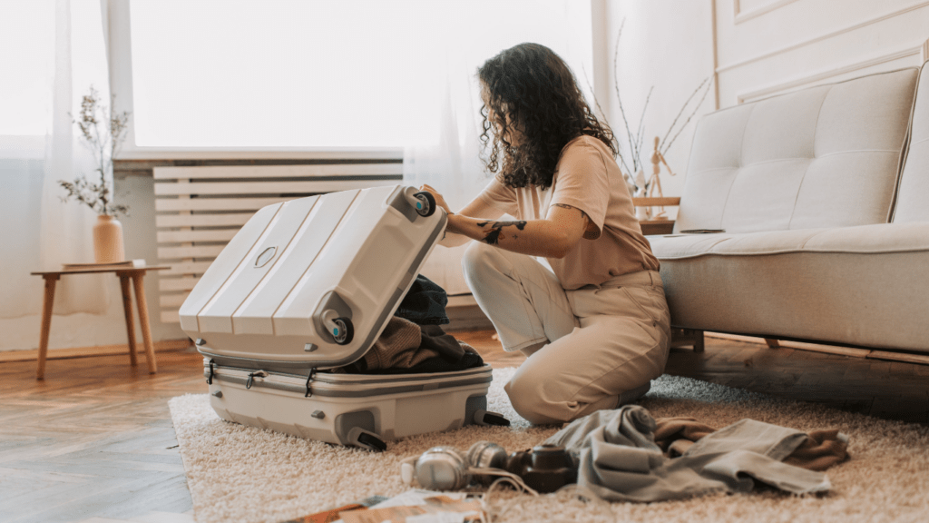 a person sitting on a bed with a suitcase full of clothes