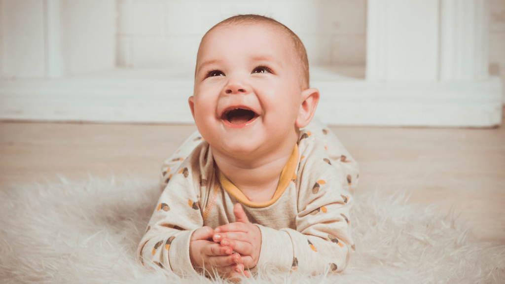 a smiling baby laying on the floor