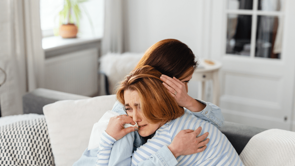 two people hugging on a couch in a living room