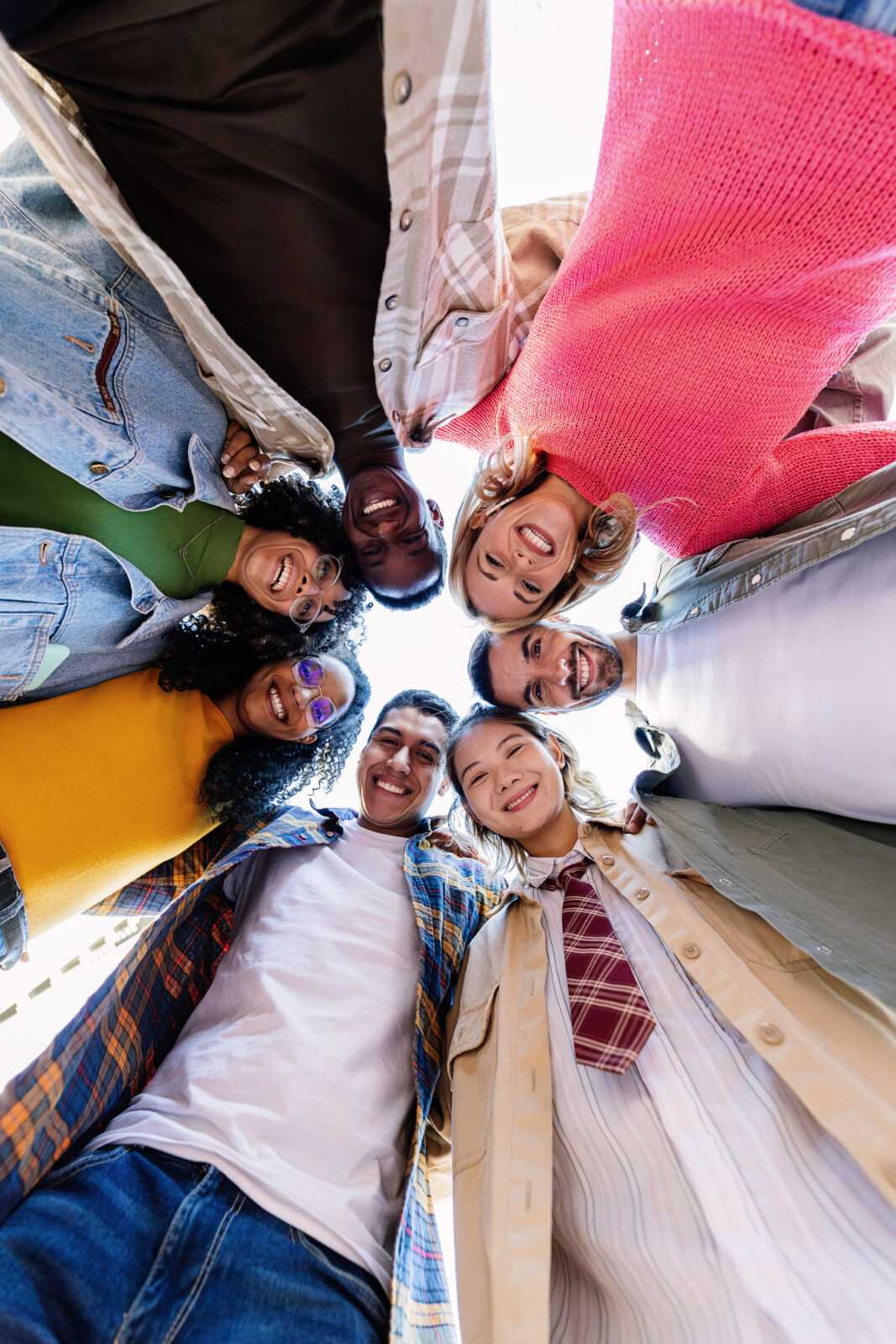 Happy young group of people smiling at camera standing in circle outside