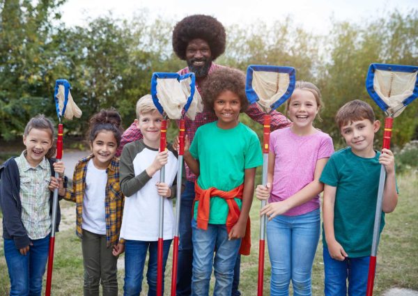 Portrait Of Team Leader And Group Of Children On Outdoor Activity Camp Catching Pond Wildlife